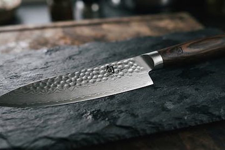 Hammered Damascus KAI chef knife on dark slate