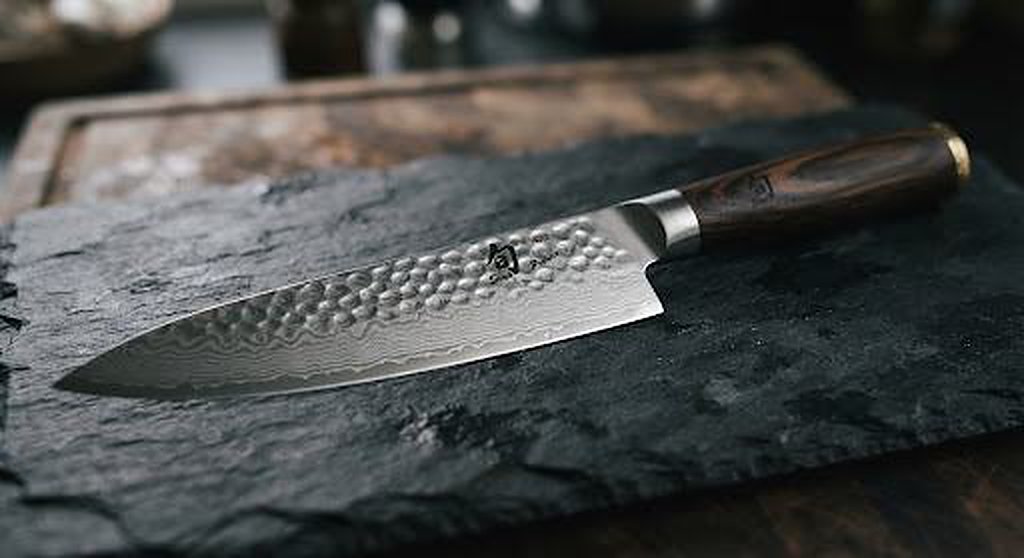 Hammered Damascus KAI chef knife on dark slate